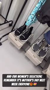 Pair of black shoes on a wooden block with a blue ribbon, likely for Mother's Day.